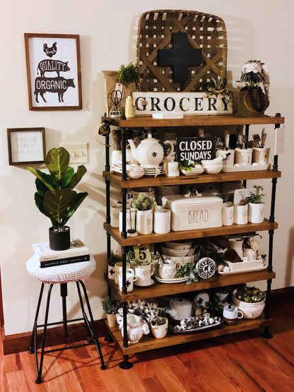 JT Industrial Designs photo by a customer of bookcase unit measuring 60inches long by 14 inches deep wide and 5 shelves tall with custom spacing siderails to be 61 inches tall. Shelves have many decorations with farmhouse rustic style and plants sit on the shelves.