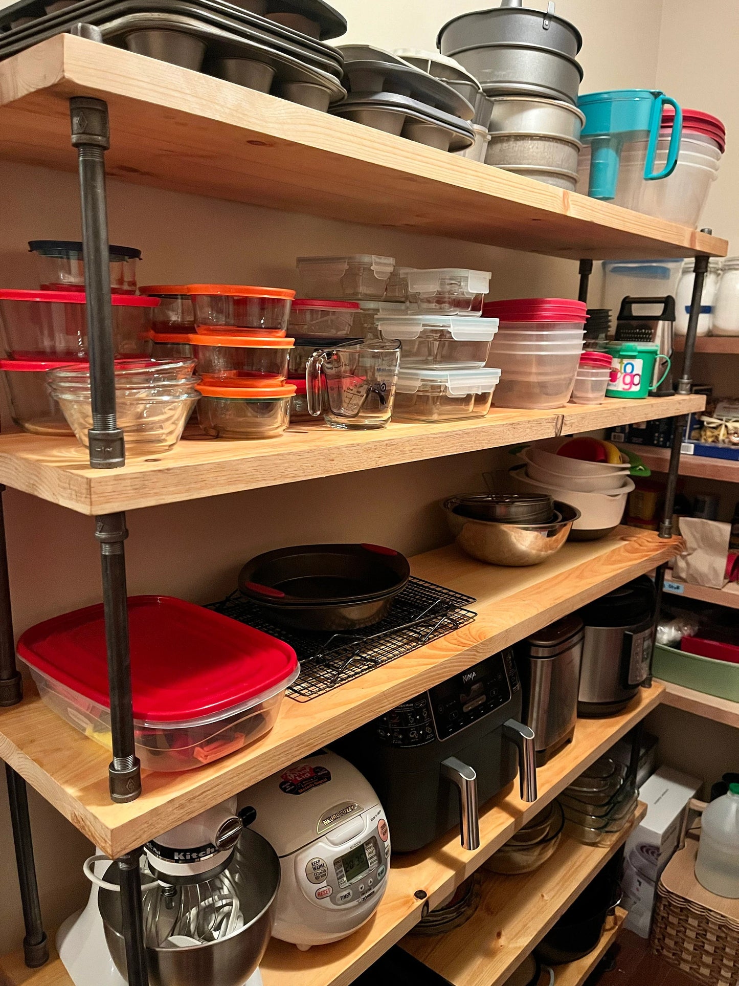 Up close angle of wide depth 14" wide bookcase shelves, handmade by JT Industrial Designs small family business, stained in color natural - a light yellow finish on solid pine wood shelving. Bookcase has many pots, pans, kitchen storage, pantry and appliances on the shelves.