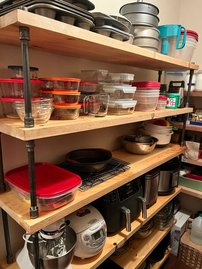 Up close angle of wide depth 14" wide bookcase shelves, handmade by JT Industrial Designs small family business, stained in color natural - a light yellow finish on solid pine wood shelving. Bookcase has many pots, pans, kitchen storage, pantry and appliances on the shelves.